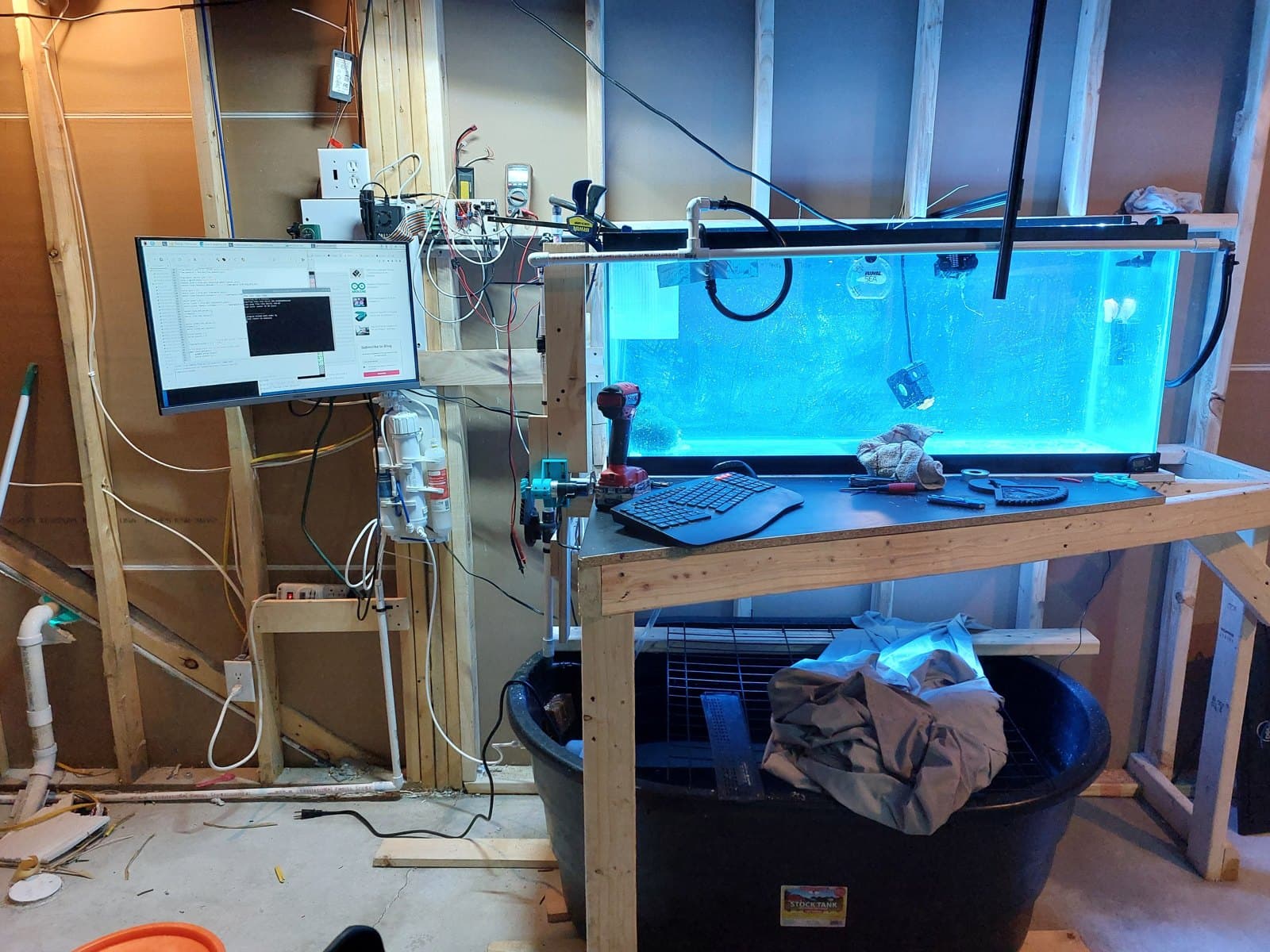 The aquarium on its stand behind the wall, the Pi and its monitor beside it