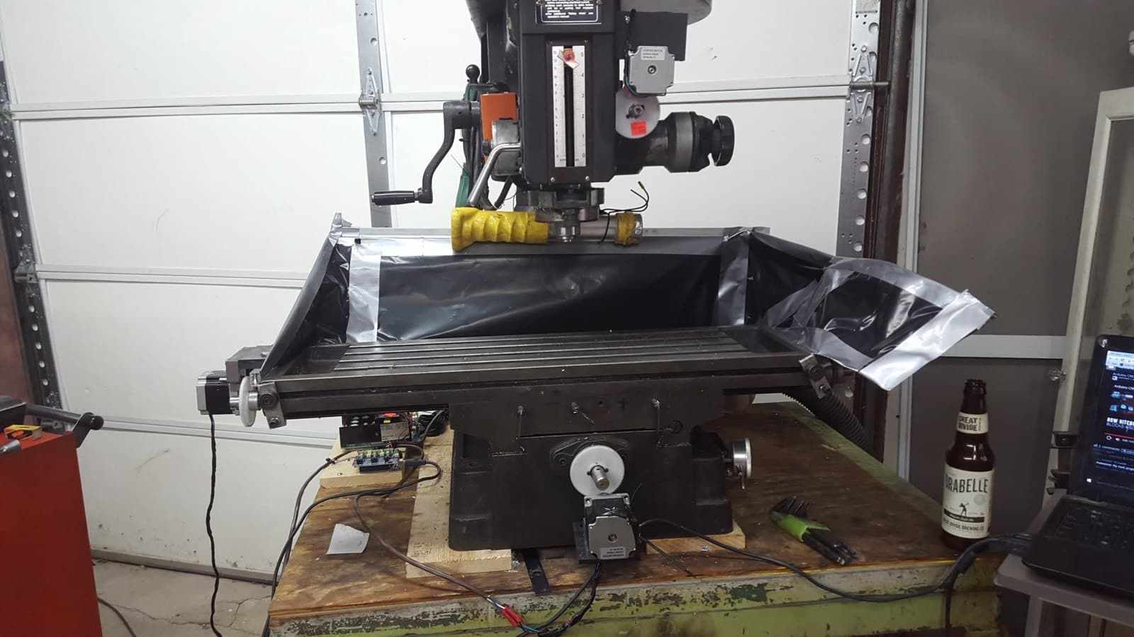 Benchtop mill with bellows covers on the table, converted to CNC